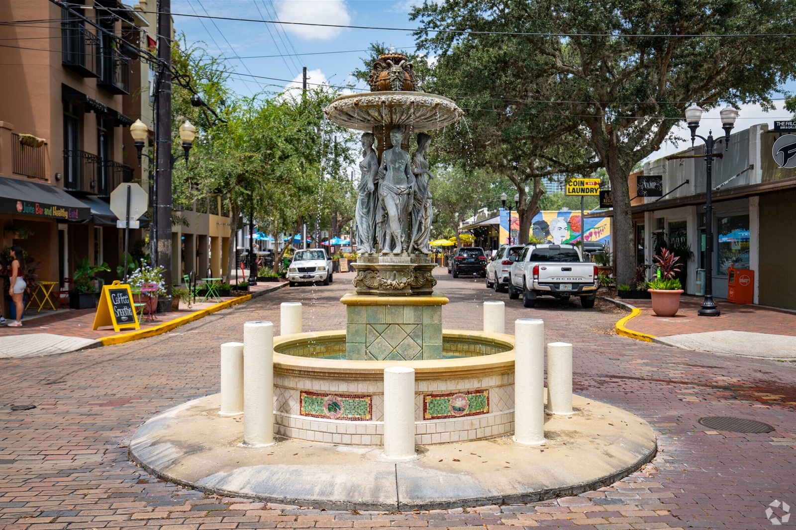 A cobbled street with buildings either side and a small fountain in the middle 